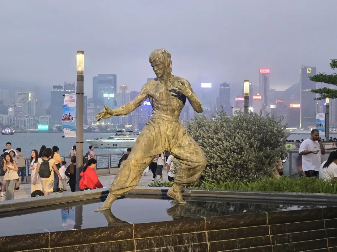 Bruce Lee statue in front of the Hong Kong harbour skyline.