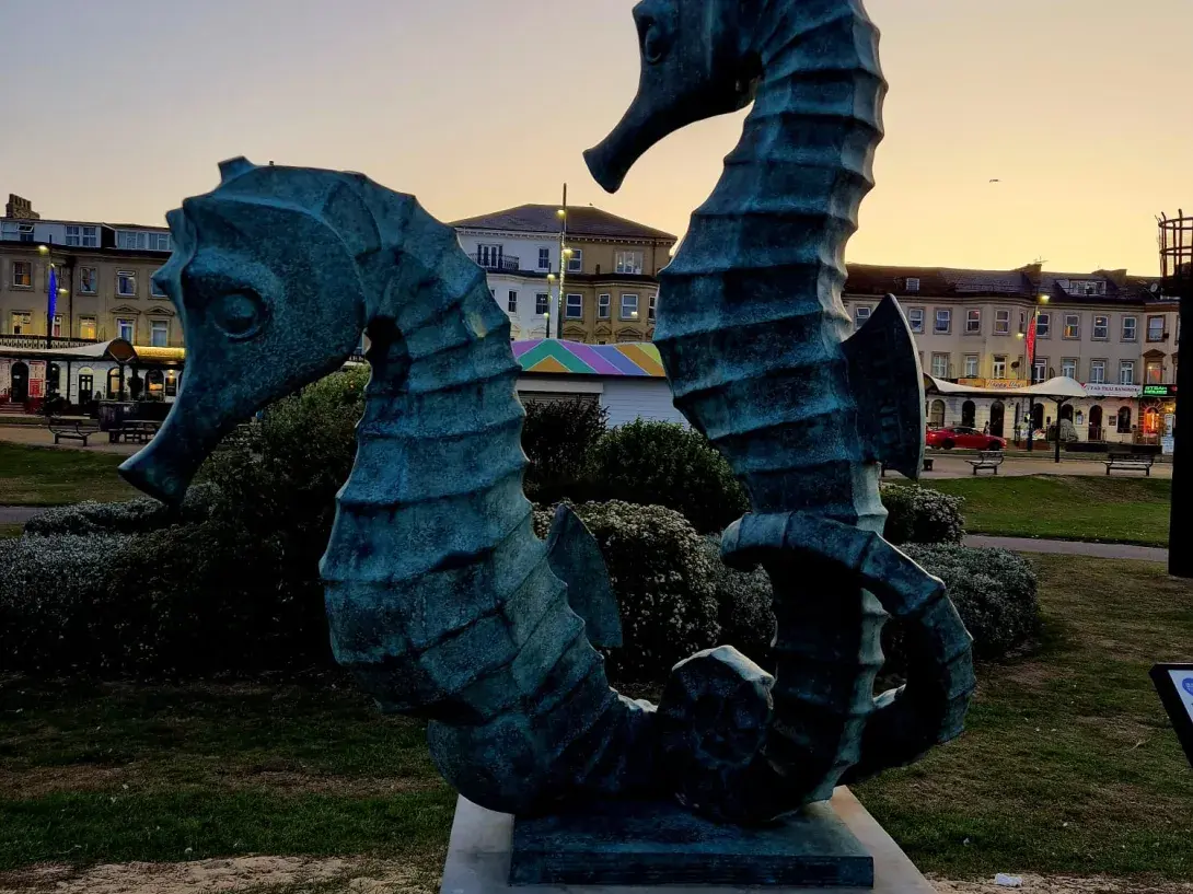 Seahorse sculpture silhouetted against a sunset